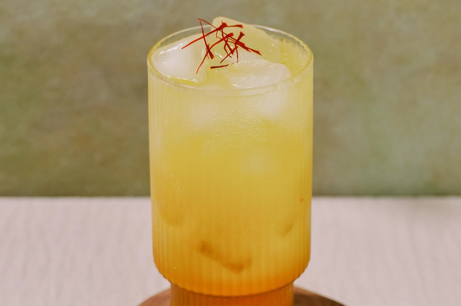 Saffron cream soda in a clear glass with saffron strands sprinkled on top