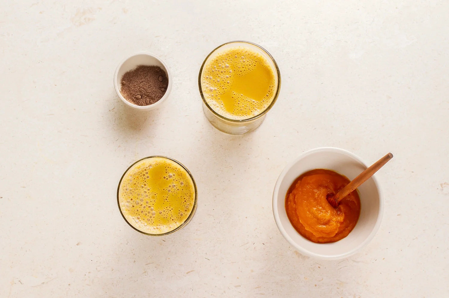 Top-down view of saffron pumpkin spice lattes made with THE FULLEST’s Warm Feelings® saffron latte powder, with pumpkin puree and spices, highlighting the vibrant yellow hues and autumnal ingredients.