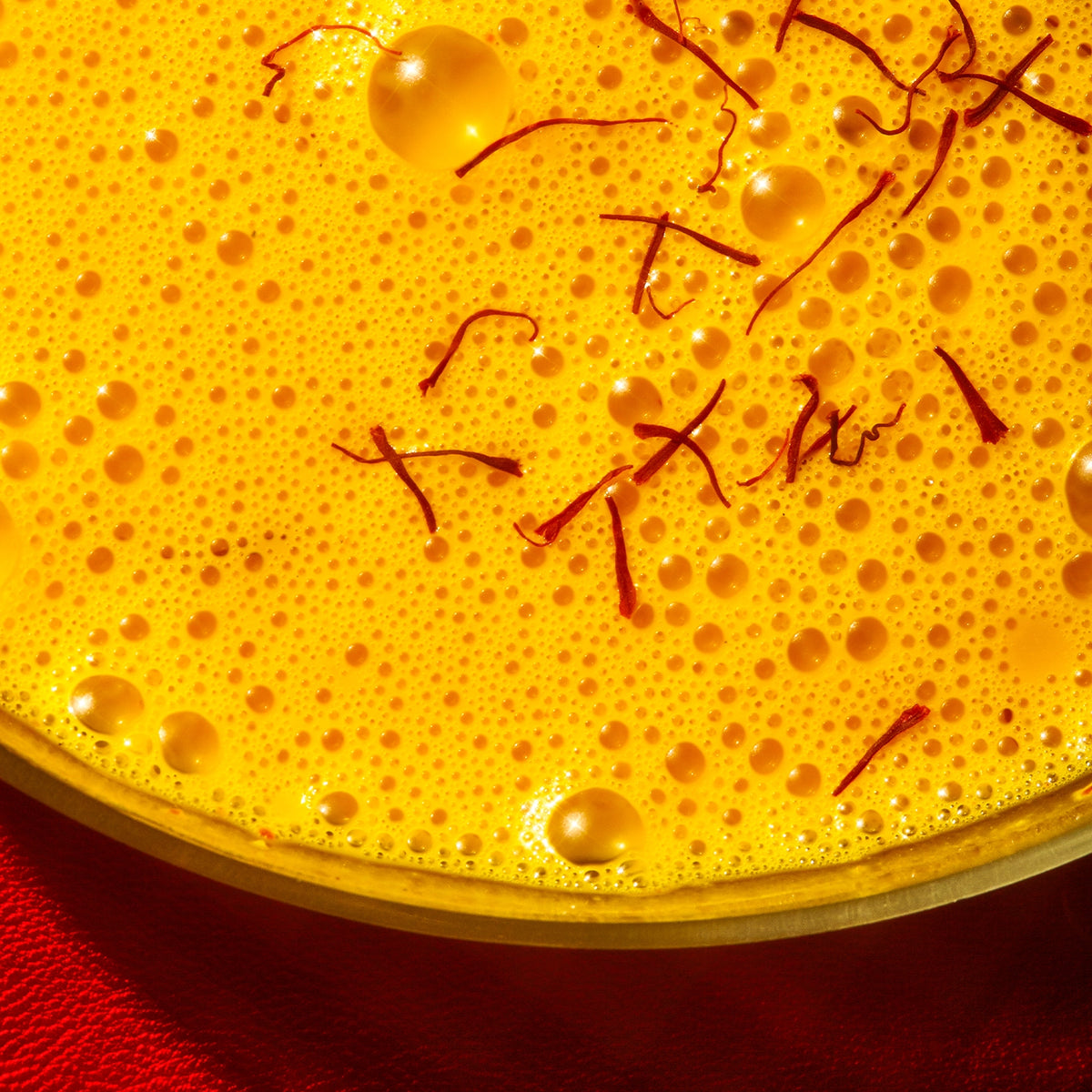 Close-up of saffron warm feelings latte liquid bubbles on a golden surface for mood improvement by THE FULLEST.