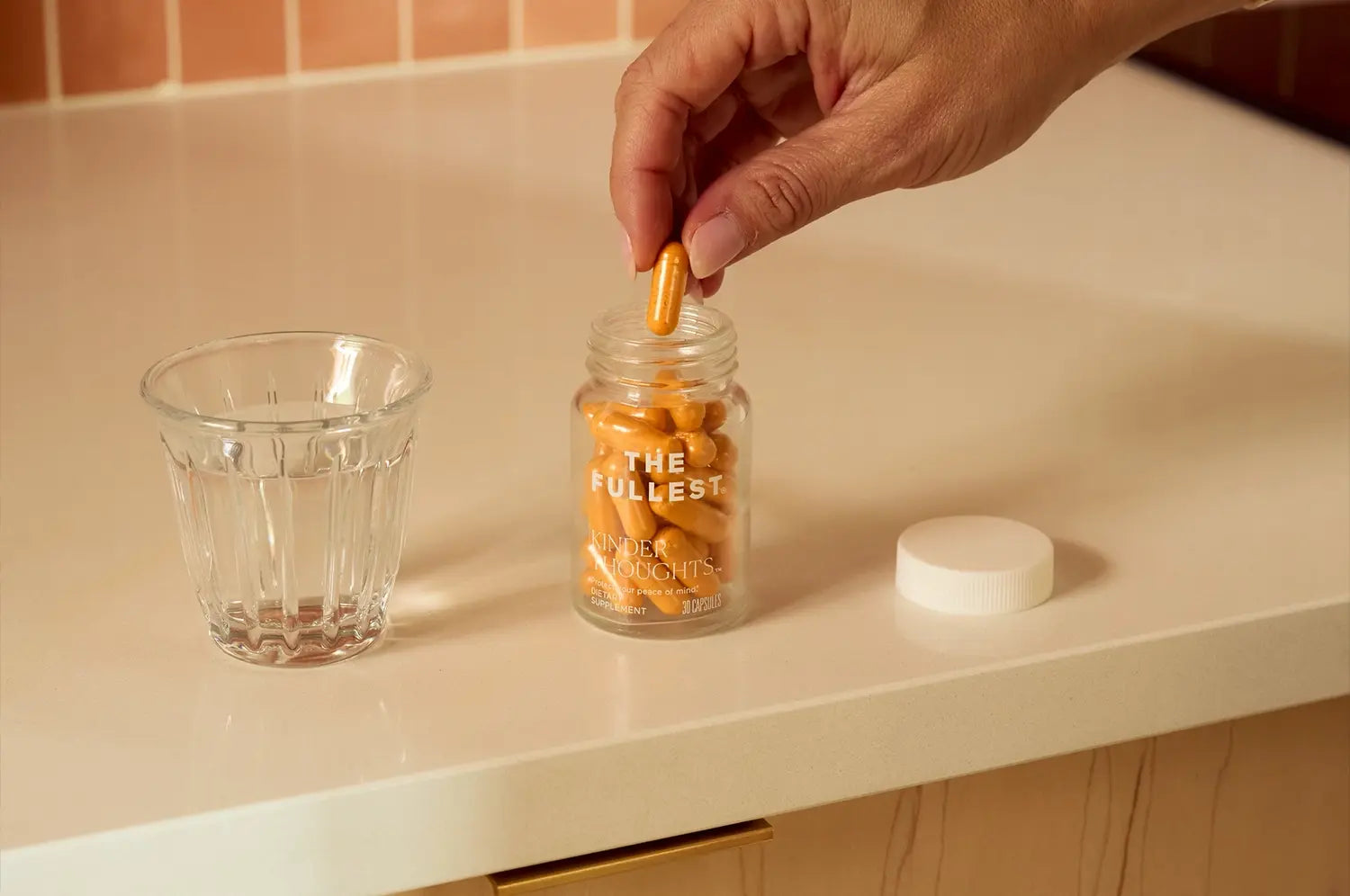 Hand reaching into a supplement bottle to grab a saffron capsule, highlighting daily wellness ritual.