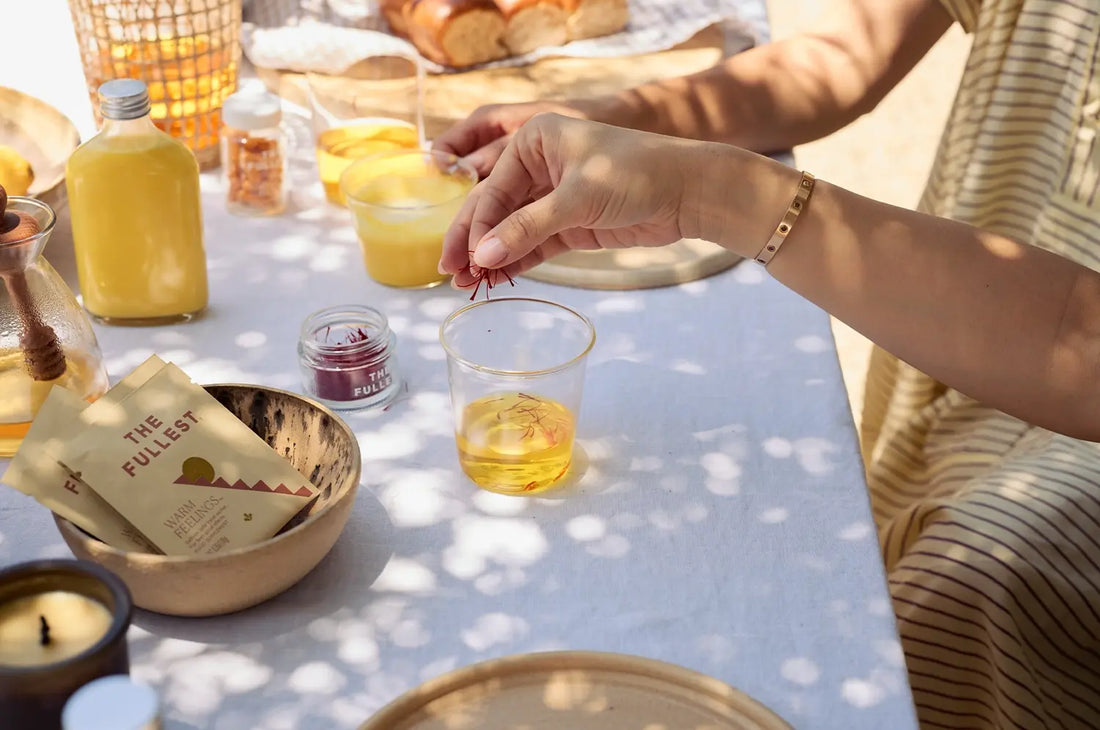 Hand sprinkling saffron threads into saffron water over a summer picnic tablescape