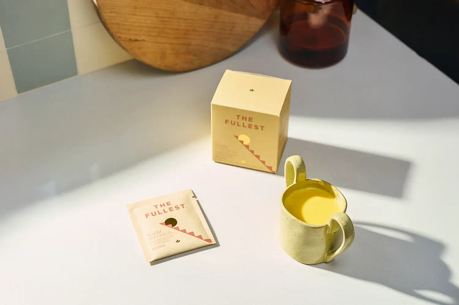 Saffron latte sachet box with a single serving sachet on the counter & mug of saffron latte