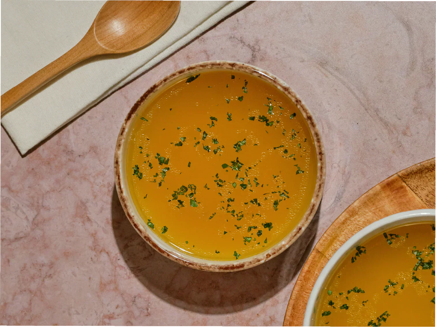 Gut healing bone broth in a ceramic mug with a wooden spoon 