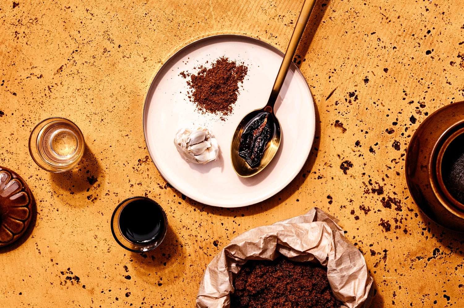 An overhead view of spices arranged on a plate with spoons sprinkled alongside on the counter.