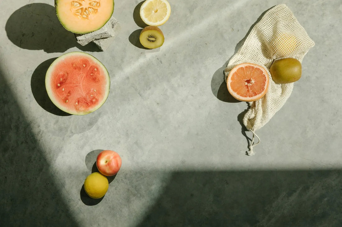 An overhead view of melons and citrus fruits arranged on a concrete counter.