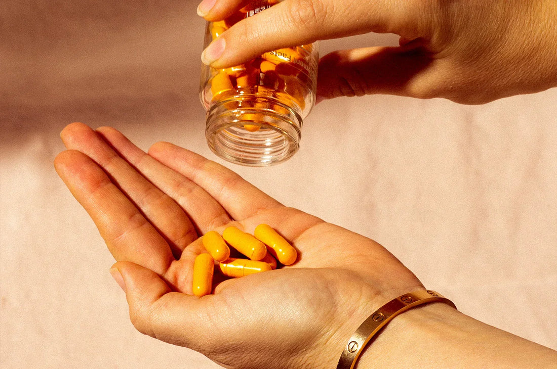An image of a woman pouring a few saffron supplements into her hand.