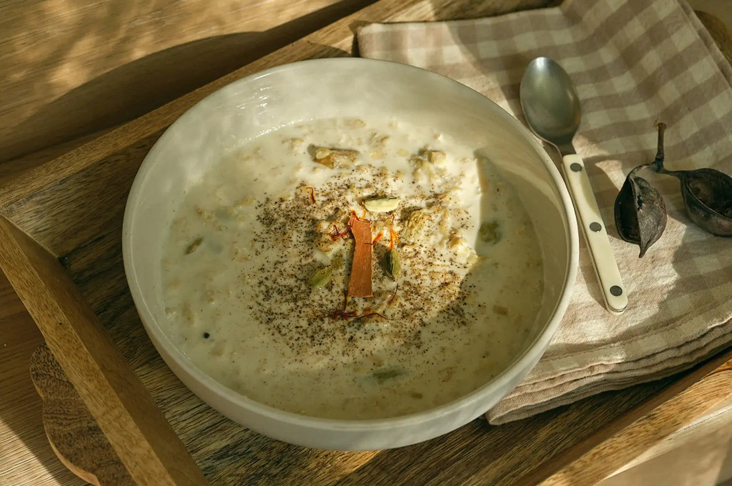 Image of Saffron Pistachio Oat Porridge in a bowl on a tray with a spoon and napkin.