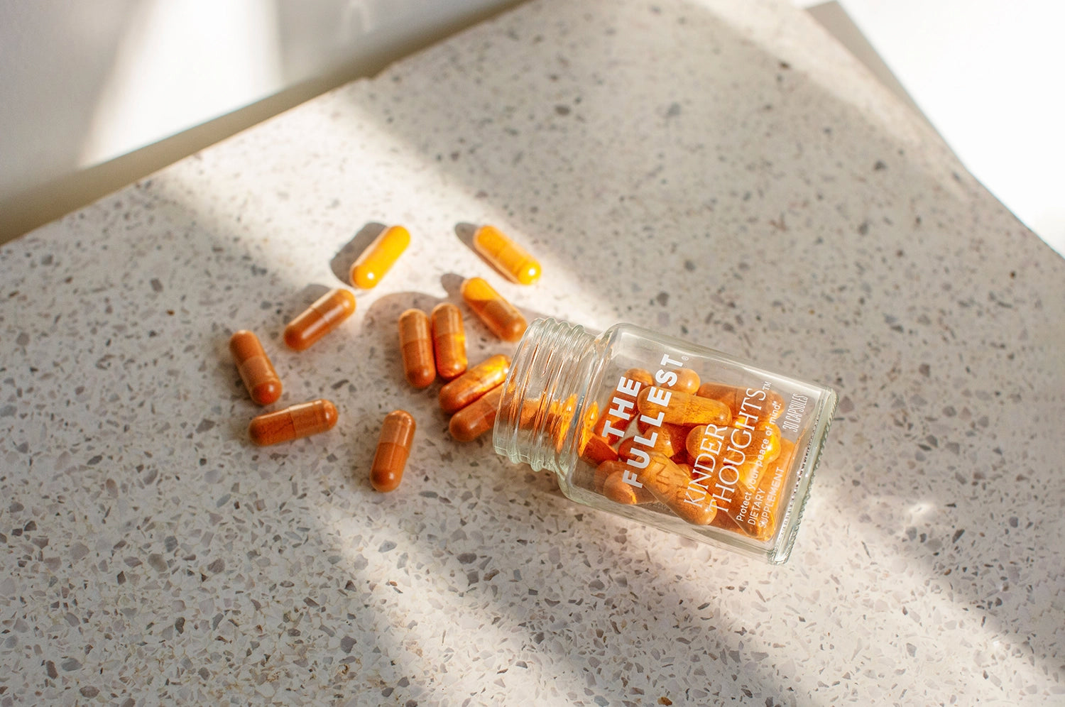 The Fullest's Kinder Thoughts saffron and turmeric bottle open, with supplements spilled and scattered across the counter.