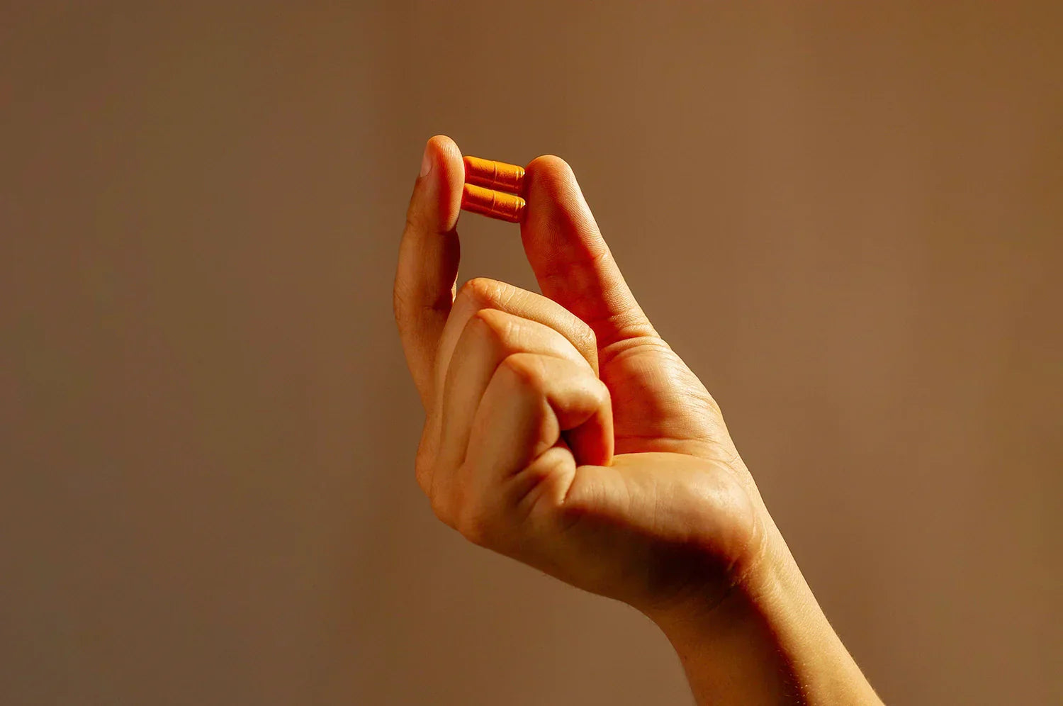 Hand holding saffron capsule on dark background