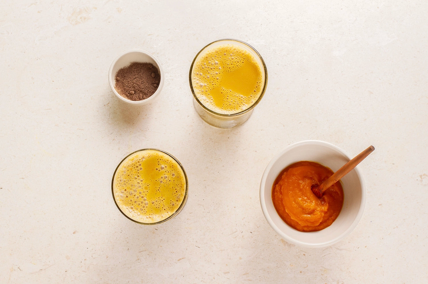 Top-down view of saffron pumpkin spice lattes made with THE FULLEST’s Warm Feelings® saffron latte powder, with pumpkin puree and spices, highlighting the vibrant yellow hues and autumnal ingredients.