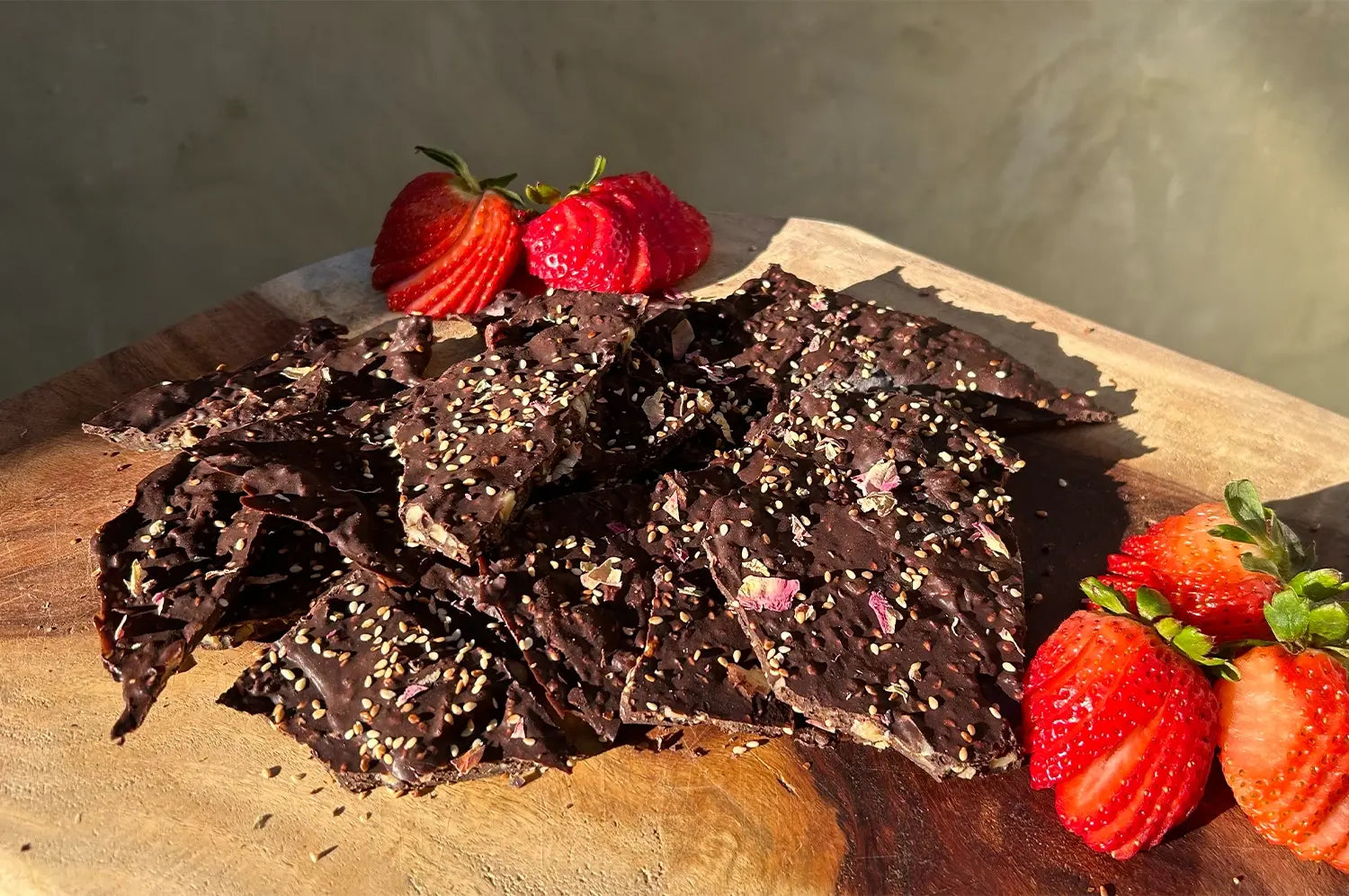 Image of chocolate bark with strawberries on a wooden cutting board in beautiful sunlight 