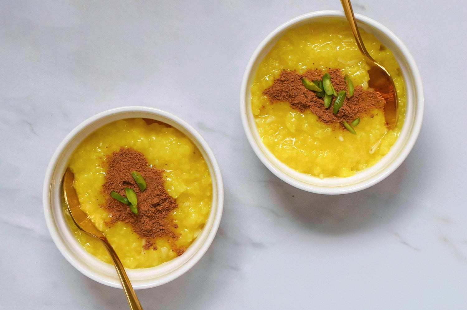 Two bowls of saffron rice pudding prepared with THE FULLEST's Warm Feelings saffron latte powder and topped with cinnamon.