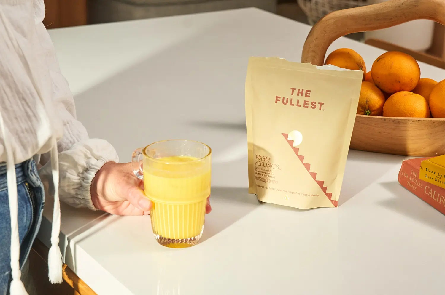 Saffron latte in a clear cup on the counter, The Fullest saffron latte bag in the background