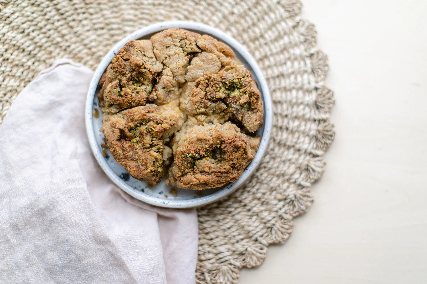 A photograph of saffron cinnamon pull-apart bread resting on a plate, placed on a woven doily.