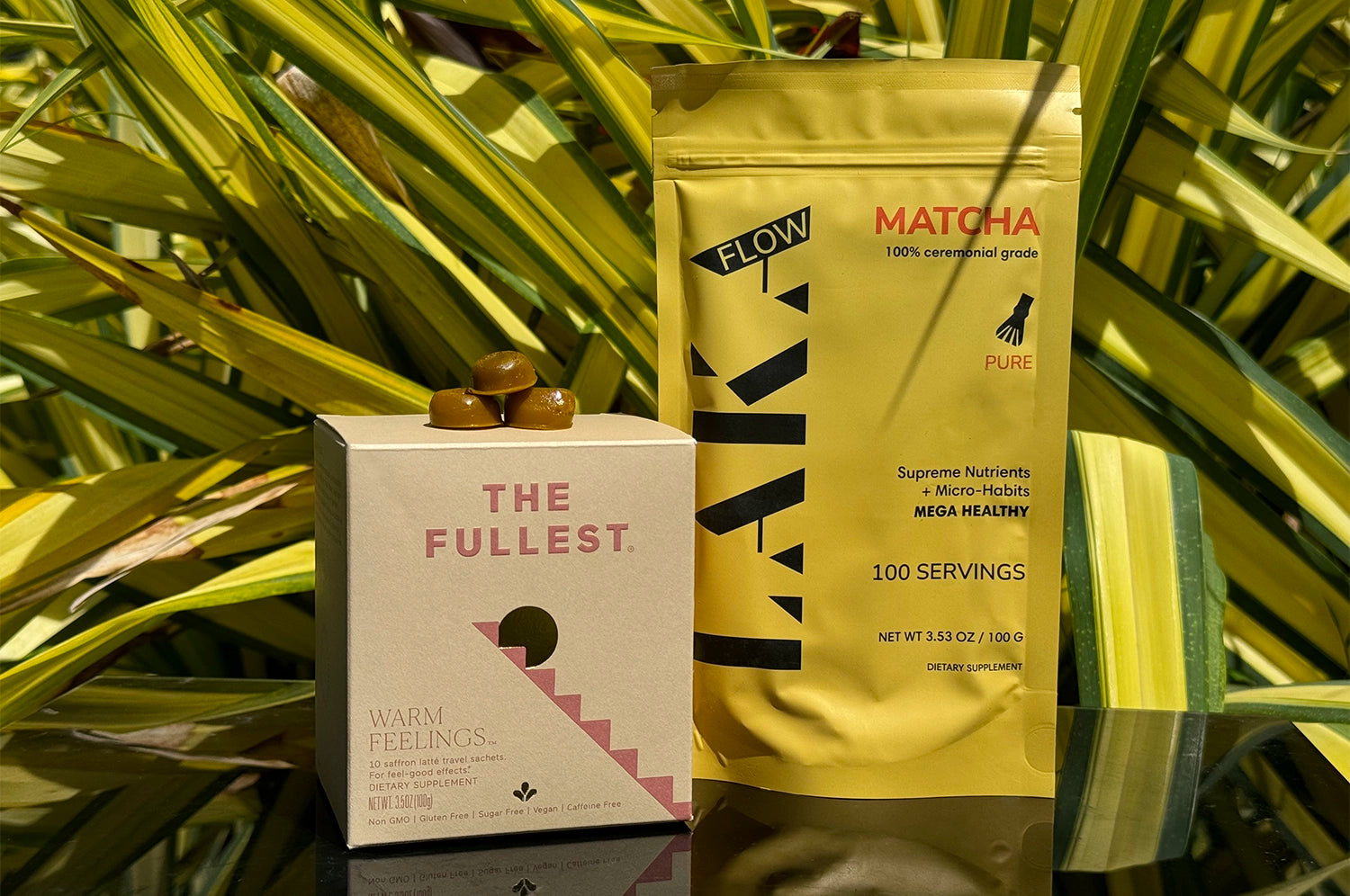 Health product packages for LAKA matcha and Warm Feelings saffron latte displayed against a background of green plant leaves.