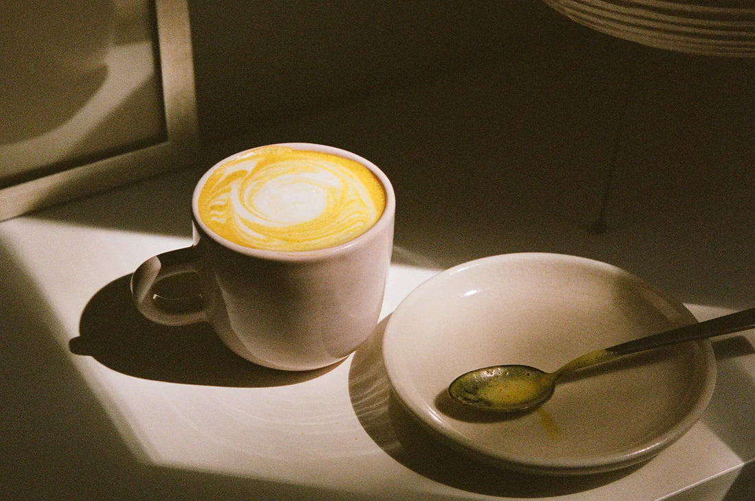 A cup of THE FULLEST  saffron latte in a patch of sunlight.
