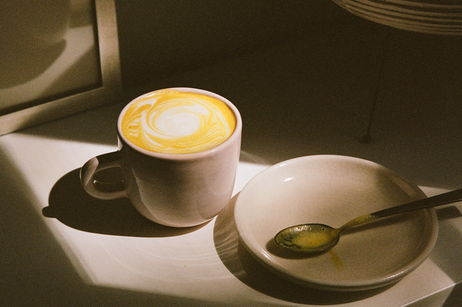 A cup of THE FULLEST Warm Feelings saffron latte in a patch of sunlight.