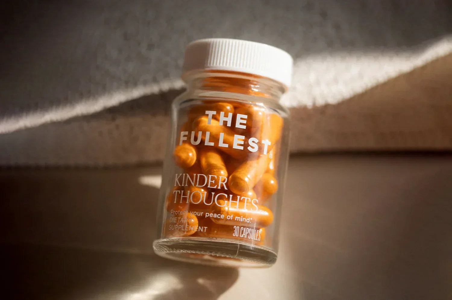 A bottle of THE FULLEST Saffron Capsules resting on an earth toned surface in the natural light.