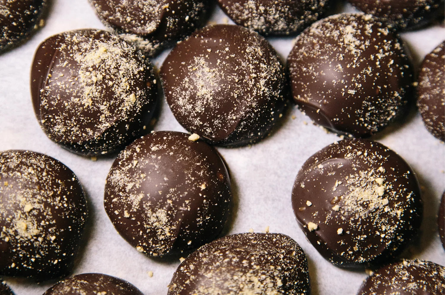 THE FULLEST Warm Feelings saffron caramel filled chocolate truffles lined up on parchment paper.