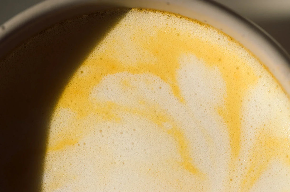 A cup of THE FULLEST Saffron Latte prepared with steamed milk in a ceramic mug.