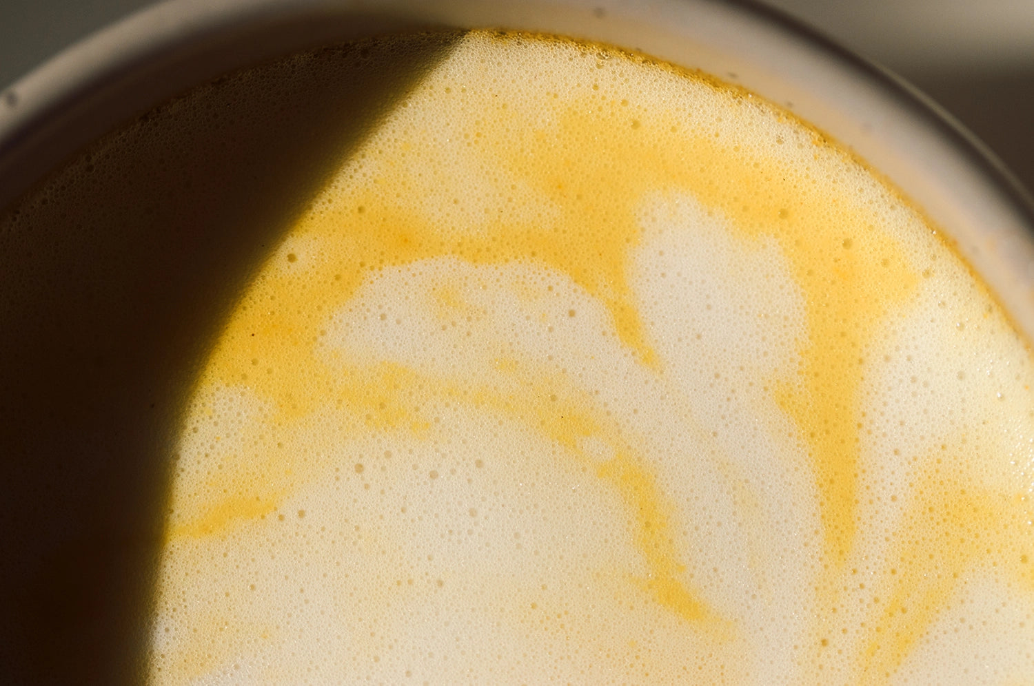 A cup of THE FULLEST's Warm Feelings saffron latte prepared with steamed milk in a ceramic mug.