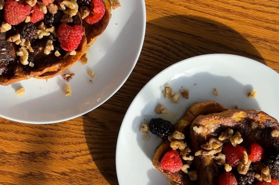 Saffron french toast with berries & crushed nuts on a wooden table with natural light 