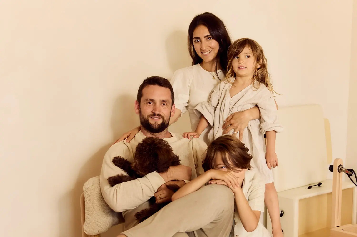 Our founder sitting with her family in front of a neutral background, smiling warmly at the camera.