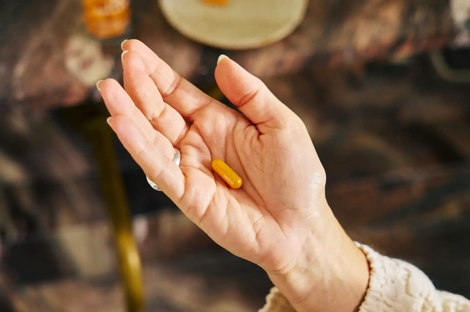 Hand holding saffron capsule over granite countertop 