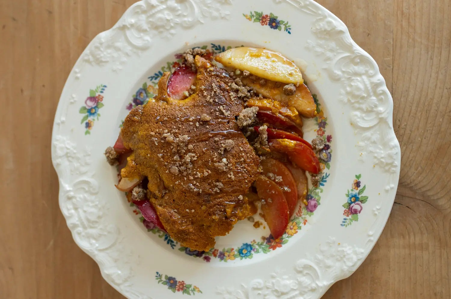 Saffron stone fruit cobbler on antique plate on a wooden counter 