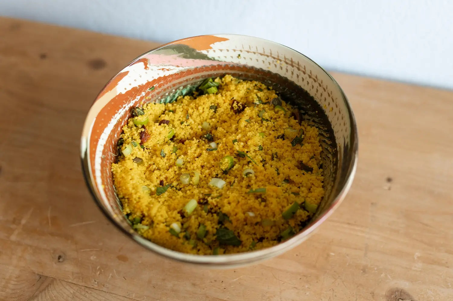 right couscous salad tossed with saffron, dried apricots, and crunchy pistachios, served in a bowl and garnished with fresh herbs—a colorful and refreshing summer dish