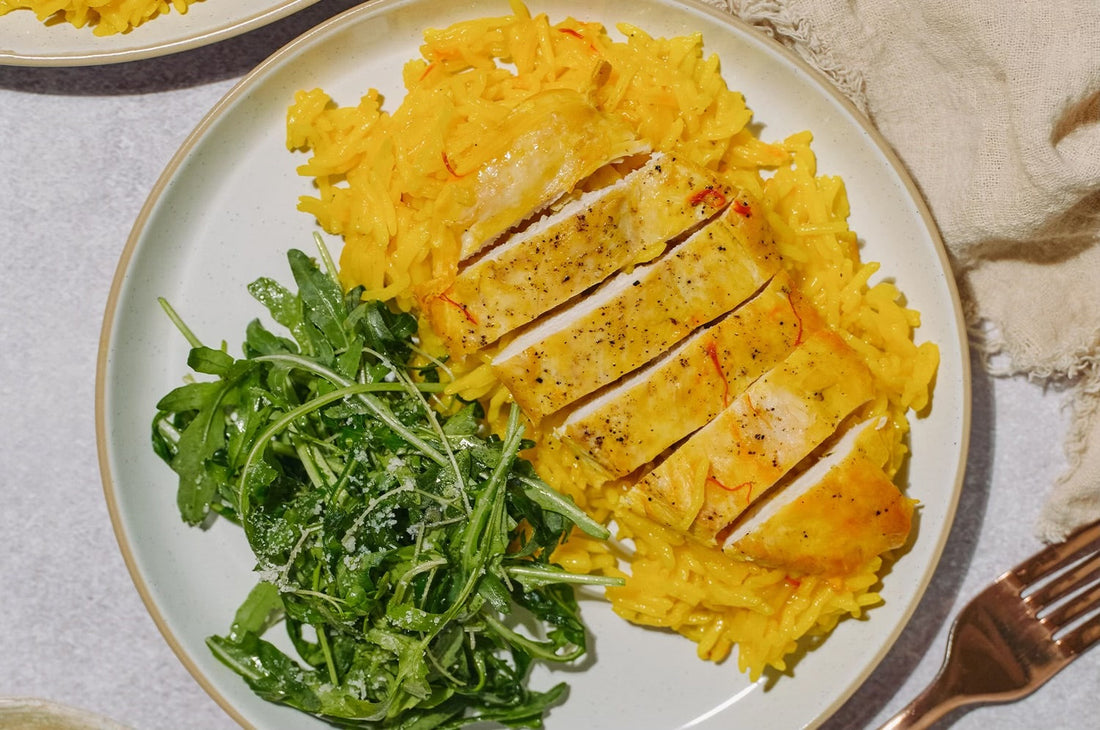 Saffron chicken & basmati rice with a side salad over a neutral background 