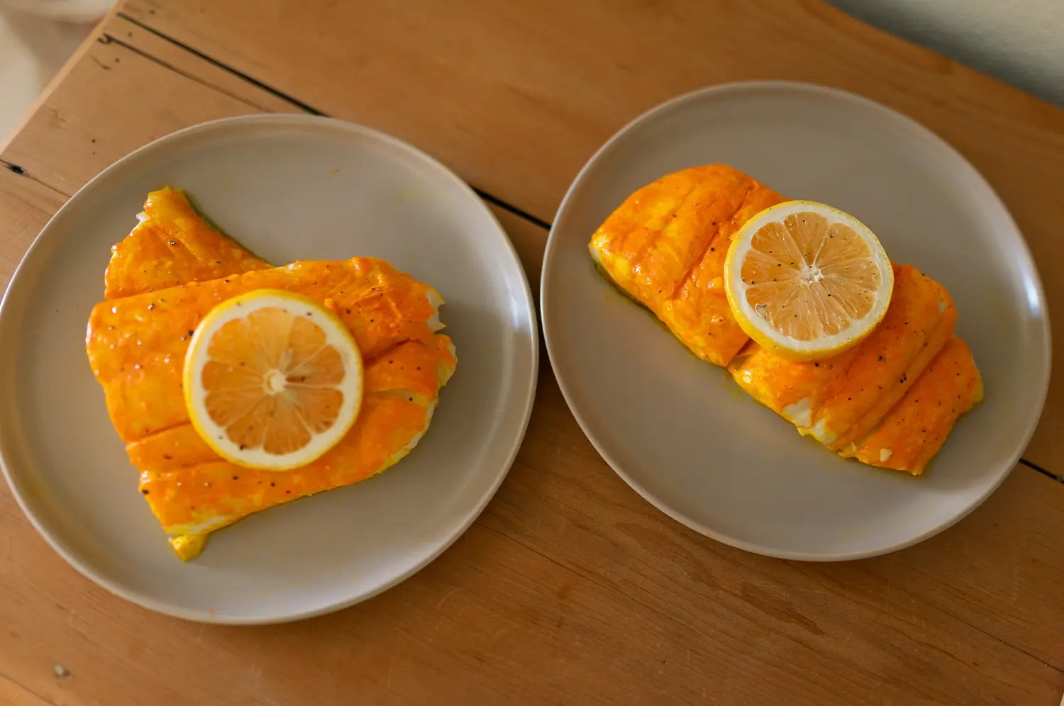 Perfectly seared halibut with a saffron glaze, topped with bright lemon slices and served on a moody dark wooden background for a rich, rustic presentation.