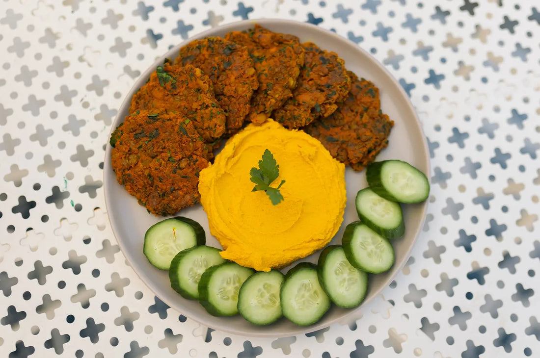 Golden-brown saffron lentil patties served with saffron hummus, fresh cucumber slices, and set against a Mediterranean-style background with warm, earthy tones.