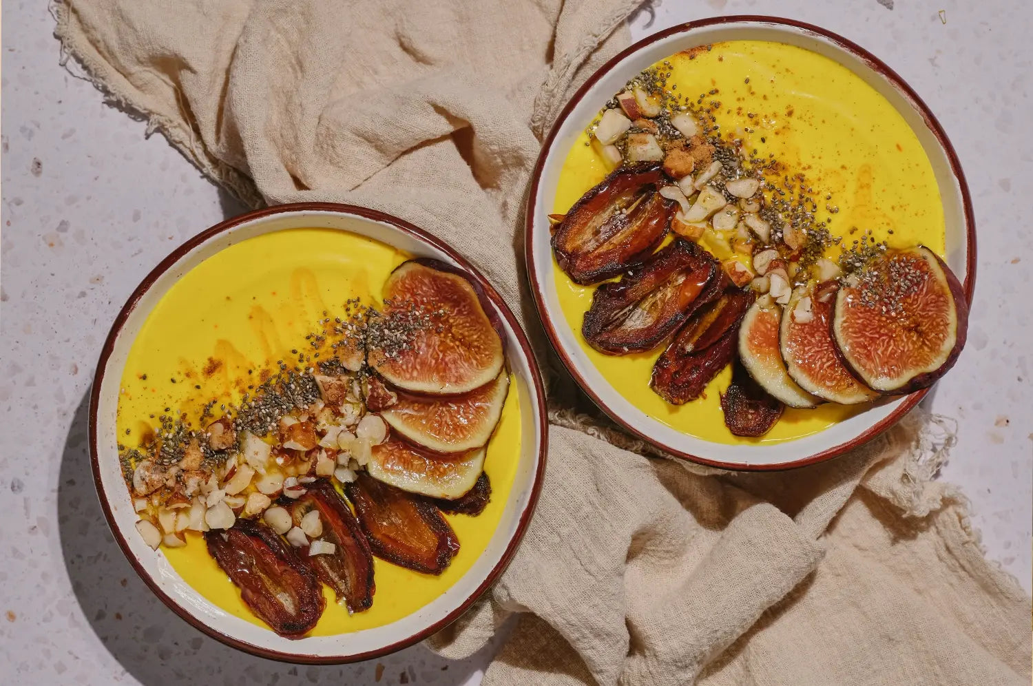 Creamy vibrant saffron yogurt bowl with pan seared dates, fresh fruit & seeds sprinkled on top