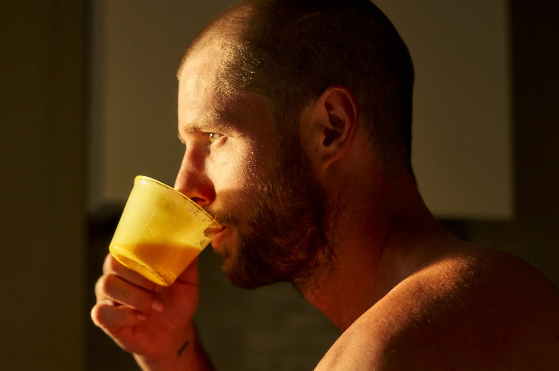 Man in sunlit kitchen, drinking a saffron latte staring out the window