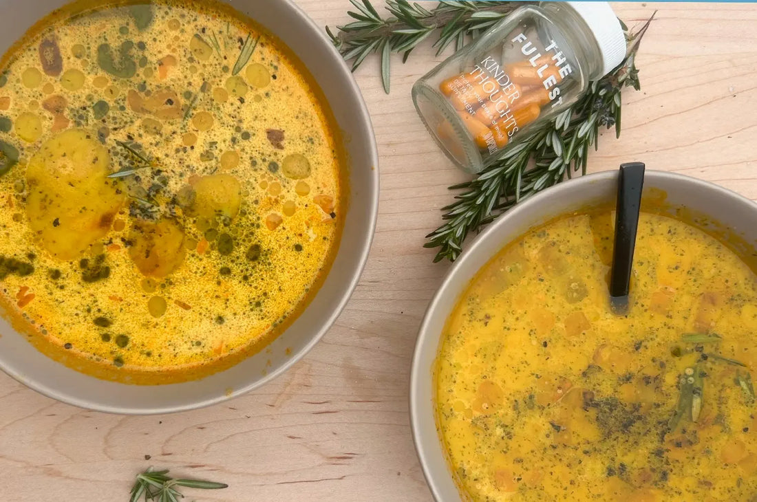 A bowl of creamy white bean and leek soup with a golden saffron tint, garnished with fresh herbs, served in a rustic white bowl on a wooden table.