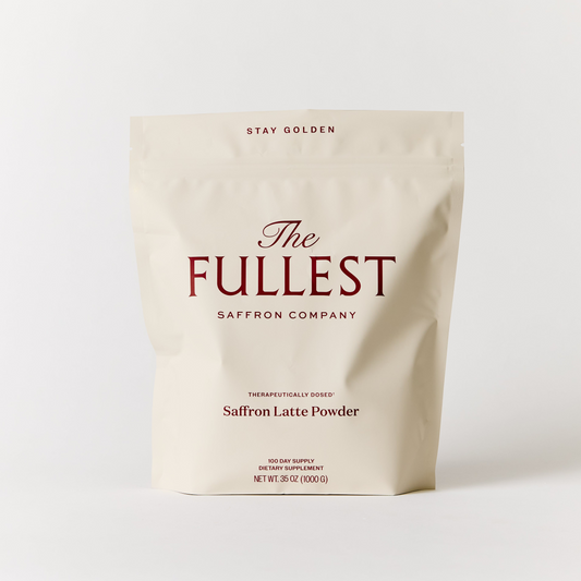 A cream-colored bag labeled "Saffron Latte 100-Day Supply" by THE FULLEST, featuring red text and set against a plain white background, showcases a caffeine-free saffron latte created to gently elevate your mood.
