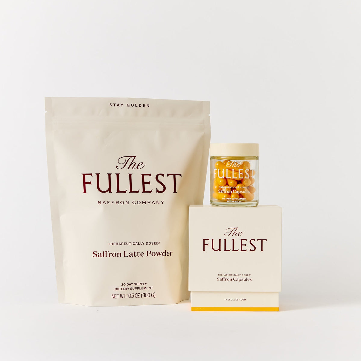 A THE FULLEST Saffron Bundle consisting of a pouch of latte powder, a box, and a glass jar of saffron capsules for restorative sleep and mood improvement.