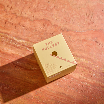 A square box labeled "THE FULLEST" rests on a pink marble surface, showcasing the luxurious Saffron Latte 10 Single-Serving Sachets inside.