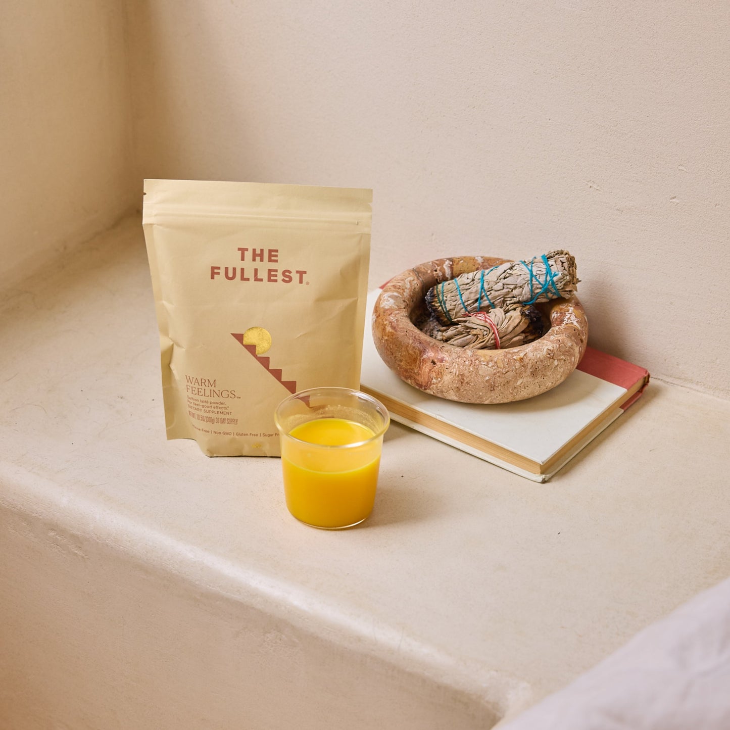 THE FULLEST Saffron Latte, served in a glass beside a notebook and sage on a light surface, offers mood support and an uplifting, caffeine-free moment.
