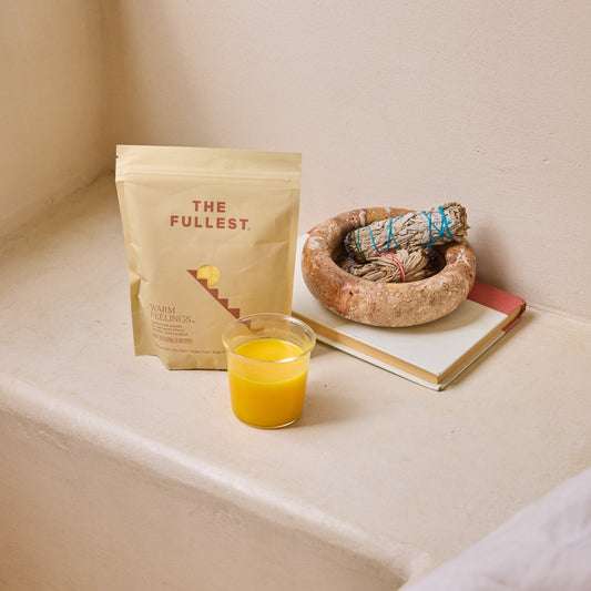 THE FULLEST Saffron Latte, served in a glass beside a notebook and sage on a light surface, offers mood support and an uplifting, caffeine-free moment.