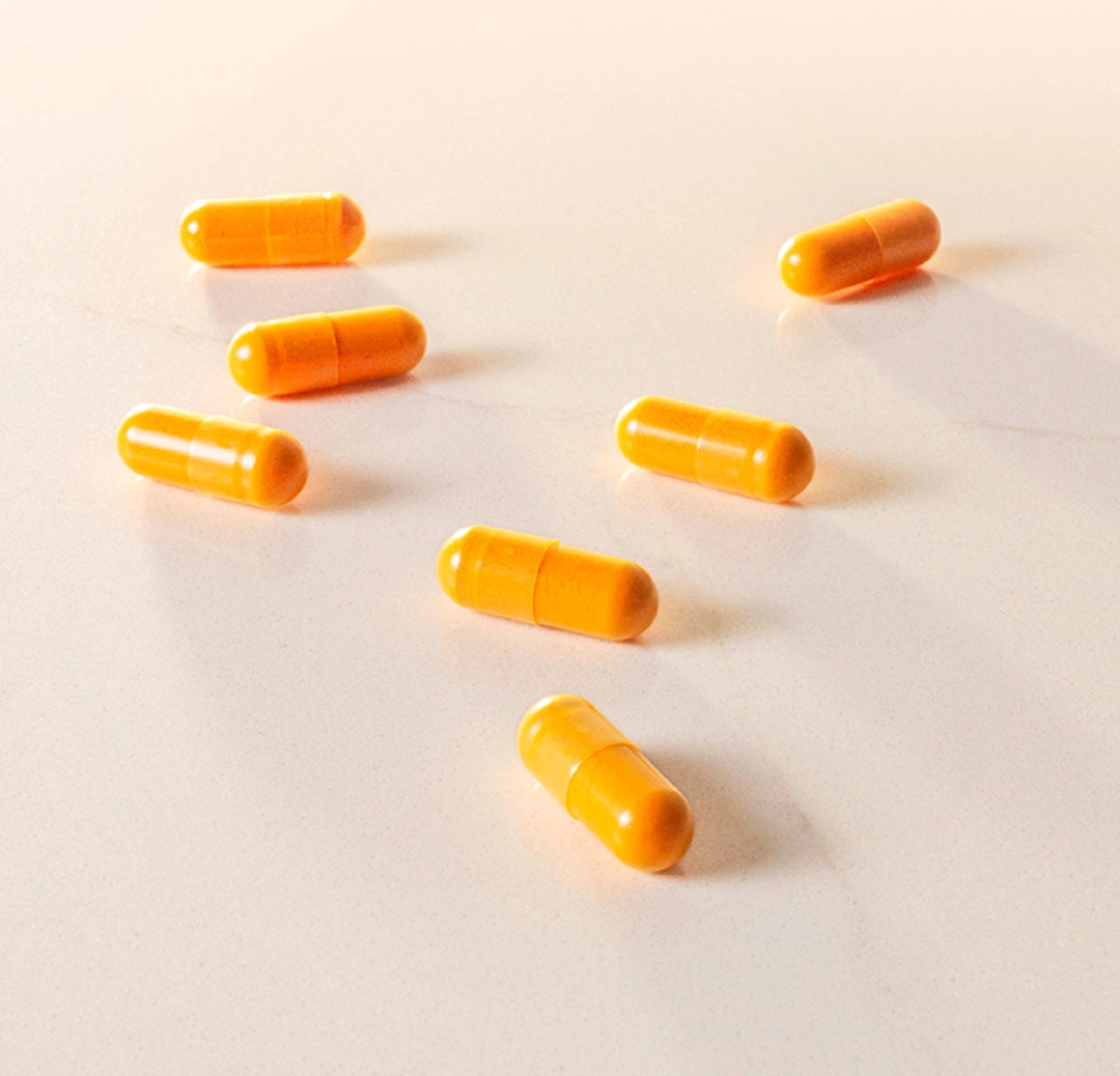THE FULLEST's Kinder Thoughts saffron capsules spilled on a white surface with warm lighting.
