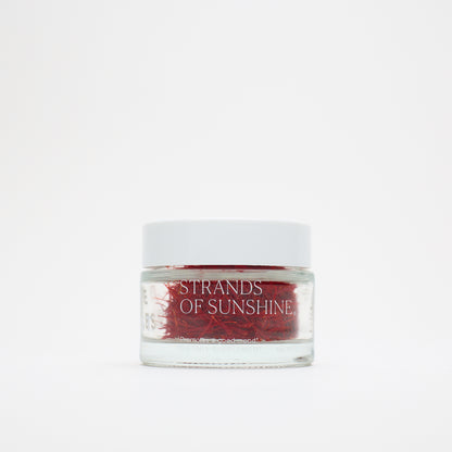 A small glass jar with a white lid, labeled "THE FULLEST Saffron Threads," holds vivid saffron strands and is set against a plain white background.