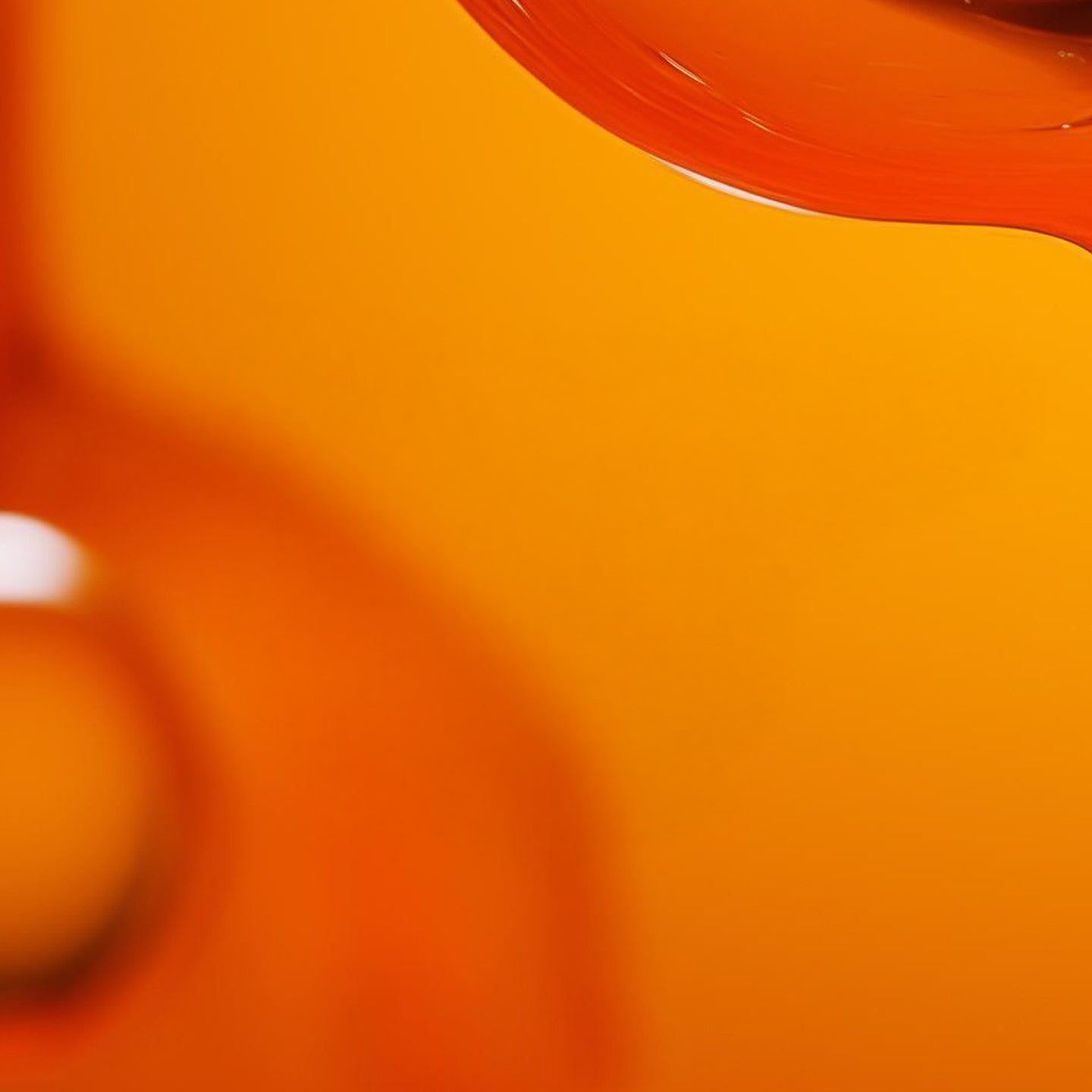Close-up of abstract orange glass objects against an orange background, with curved lines and reflections visible.