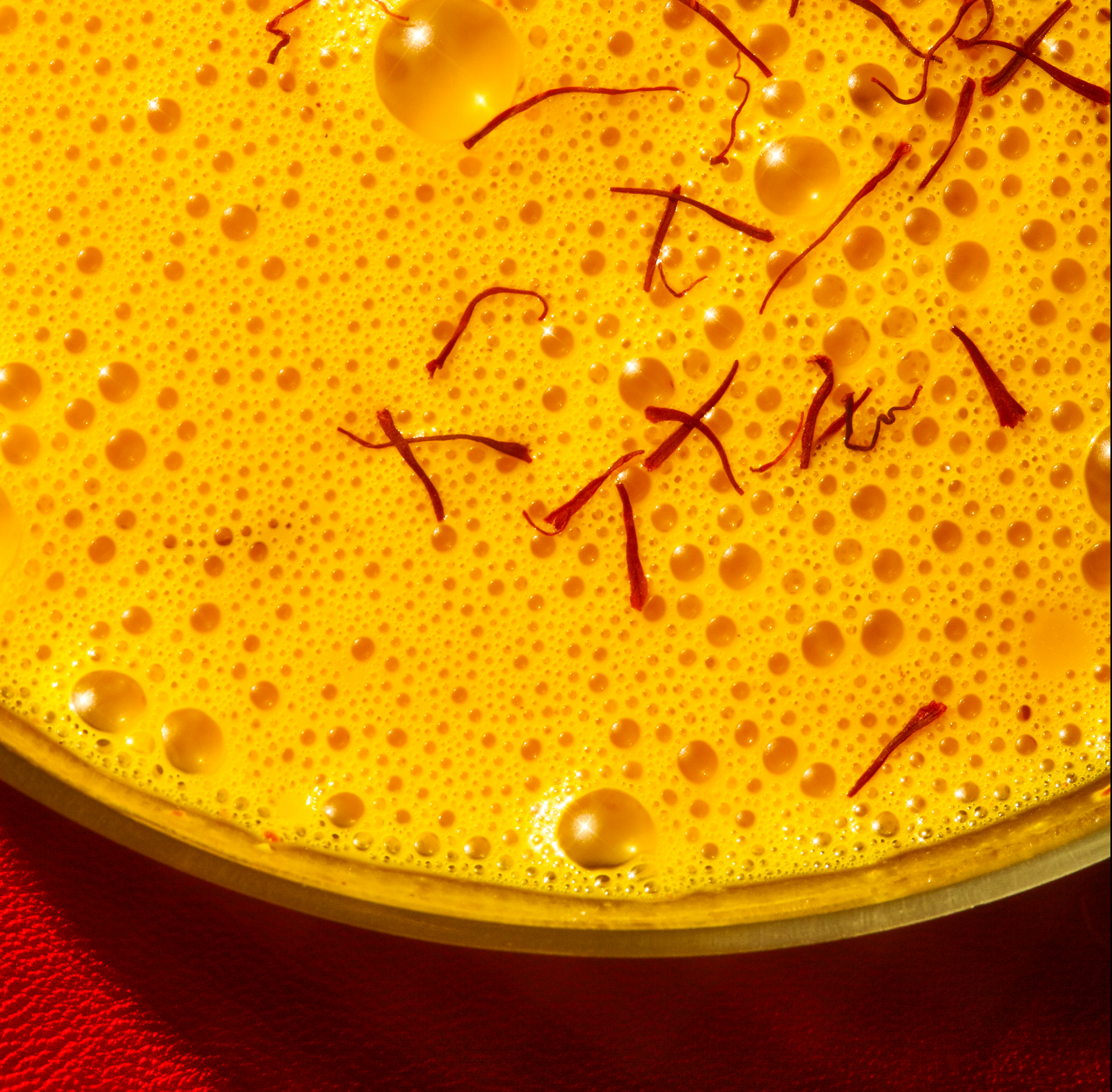 Close-up of caffeine-free Warm Feelings saffron latte with saffron threads on top.