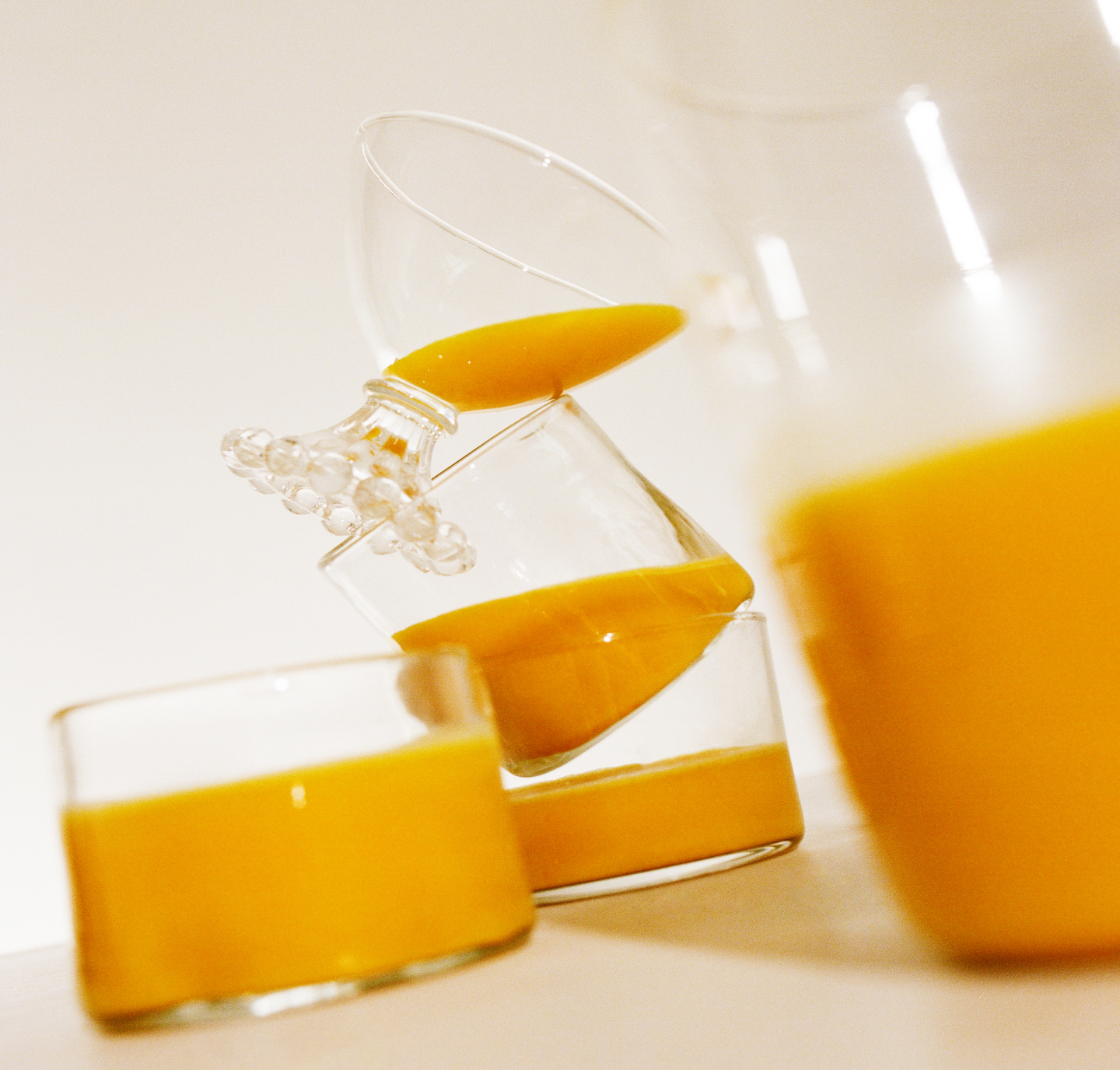 A pitcher and glasses filled with Warm Feelings latte on a table, with a dynamic pouring action captured in the frame.