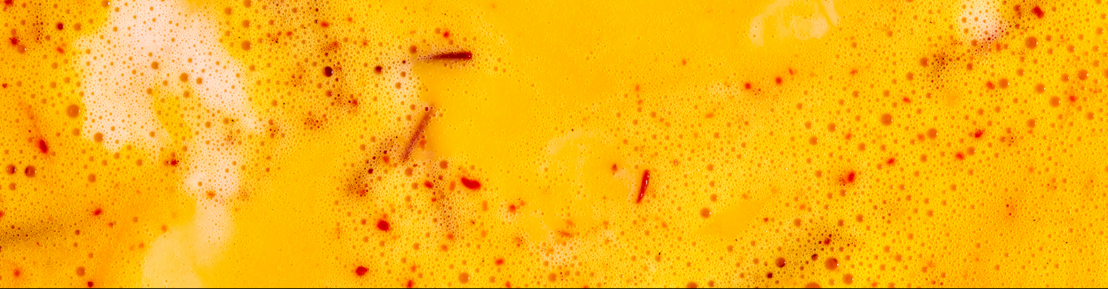 Close-up of caffeine-free Warm Feelings saffron latte with saffron threads on top.