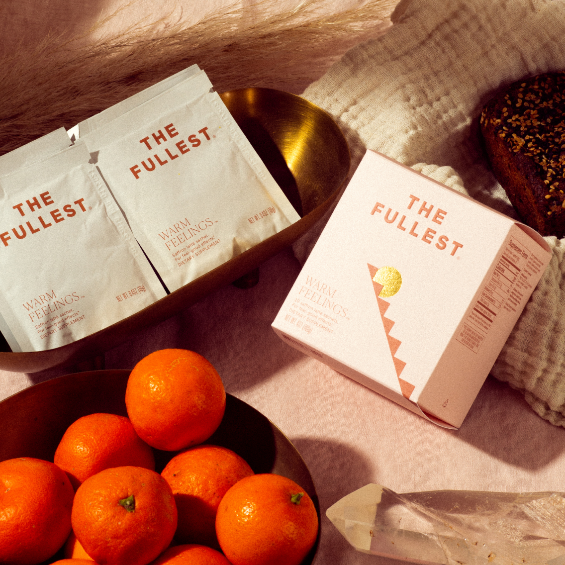 Package of "Warm Feelings Sachet" dietary supplement by THE FULLEST now available in a saffron latte flavor, with an abstract design, sharing its health-conscious features such as non-gmo, gluten-free.