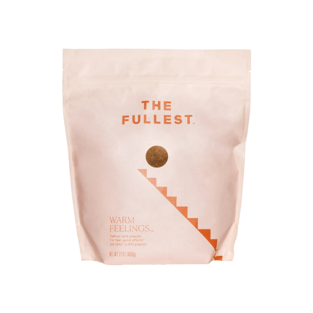 A large bag of "the fullest warm feelings" saffron latte dietary supplement in a minimalistic pink-colored package, highlighting features such as non-gmo, gluten-free, sugar-free, vegan, and caffeine-free.