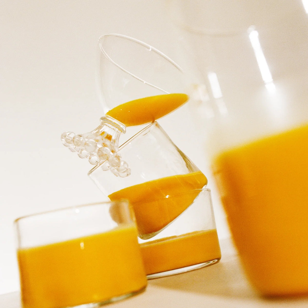 A pitcher and glasses filled with Warm Feelings latte on a table, with a dynamic pouring action captured in the frame.